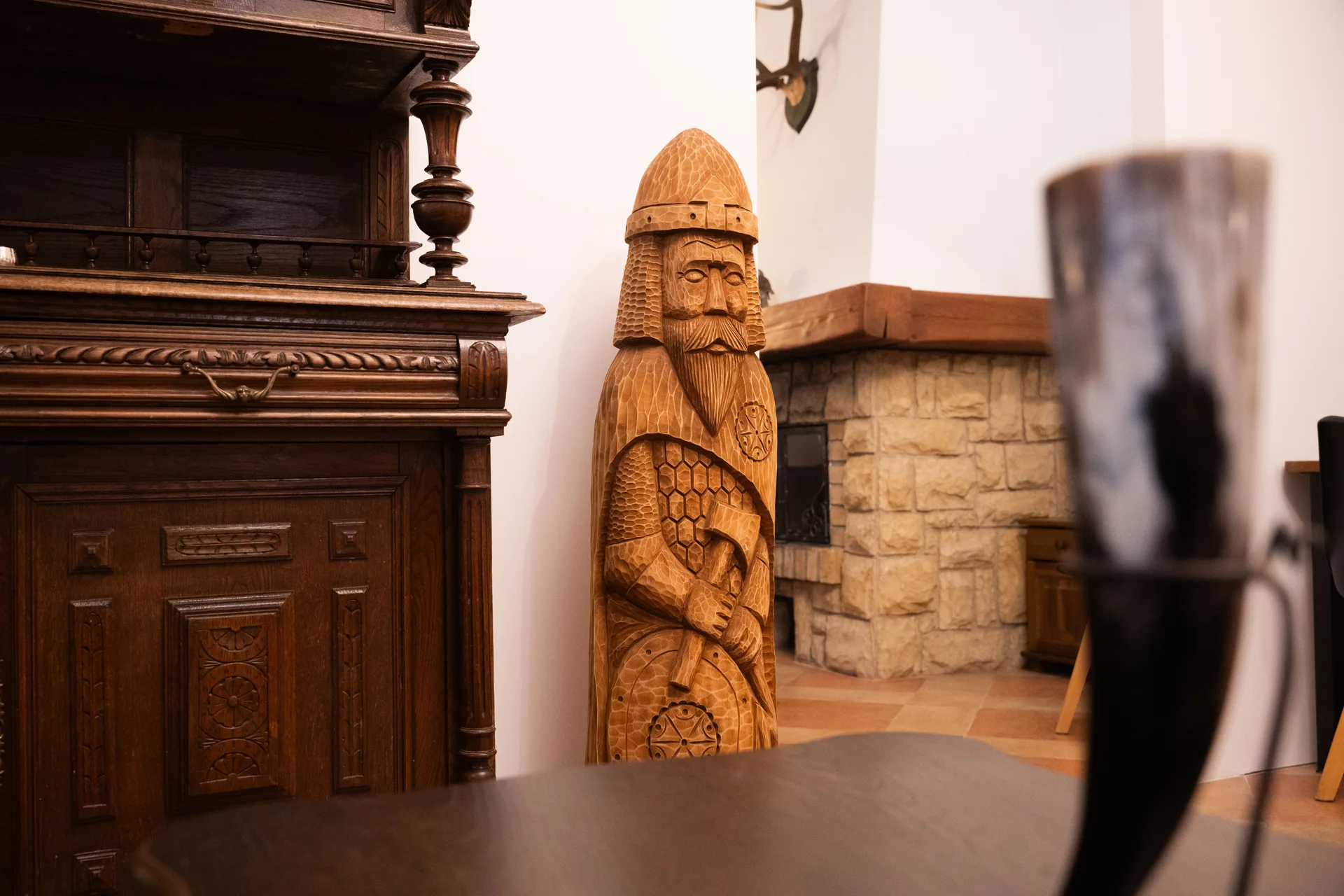 Carved wooden figure of Perun beside an antique cabinet