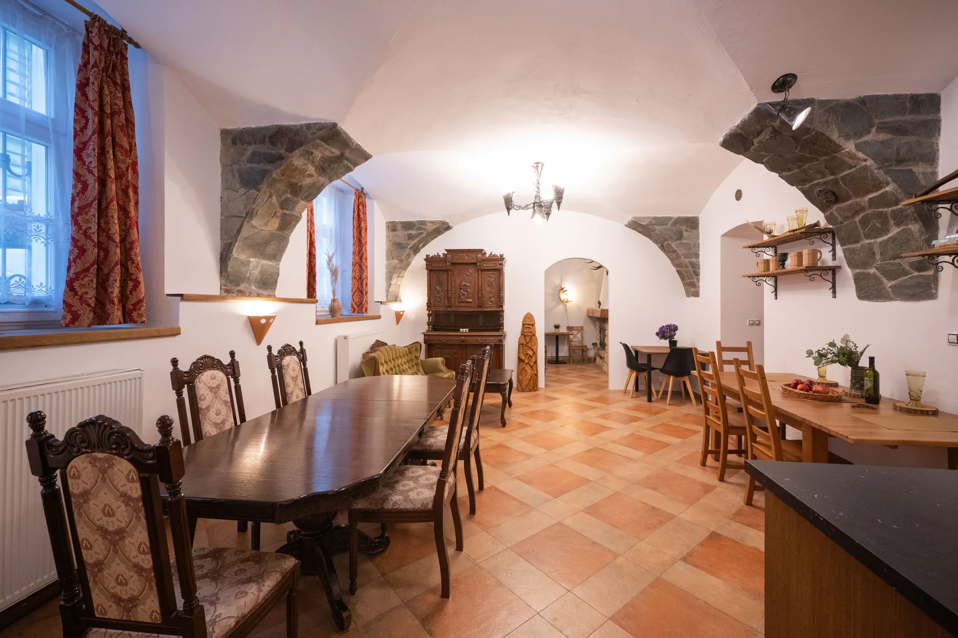 Vaulted dining room with carved wooden chairs and warm terracotta floors