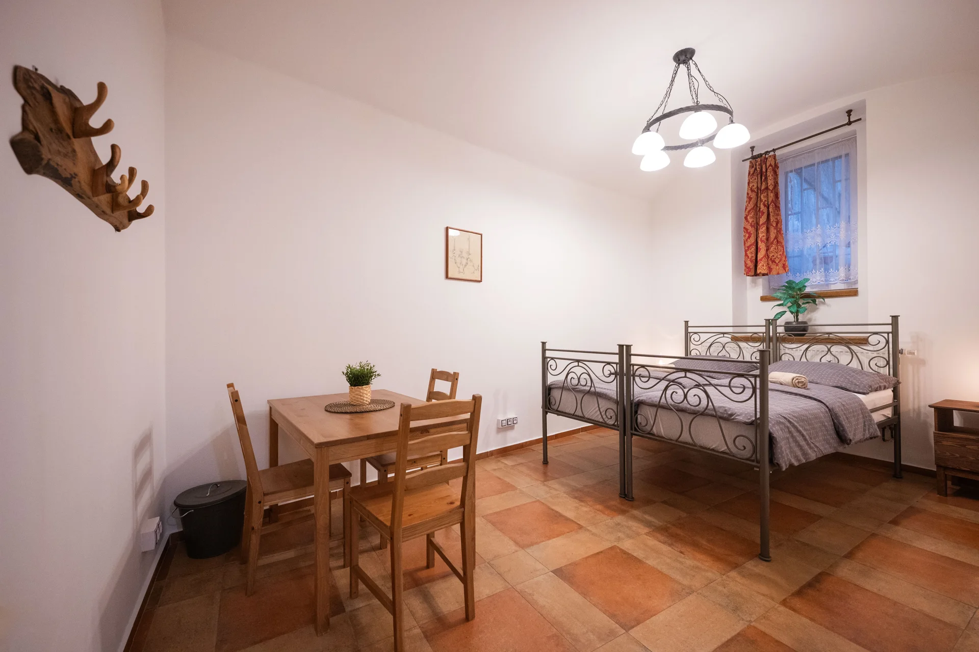 A bedroom with an iron bed frame, wooden furniture and soft daylight